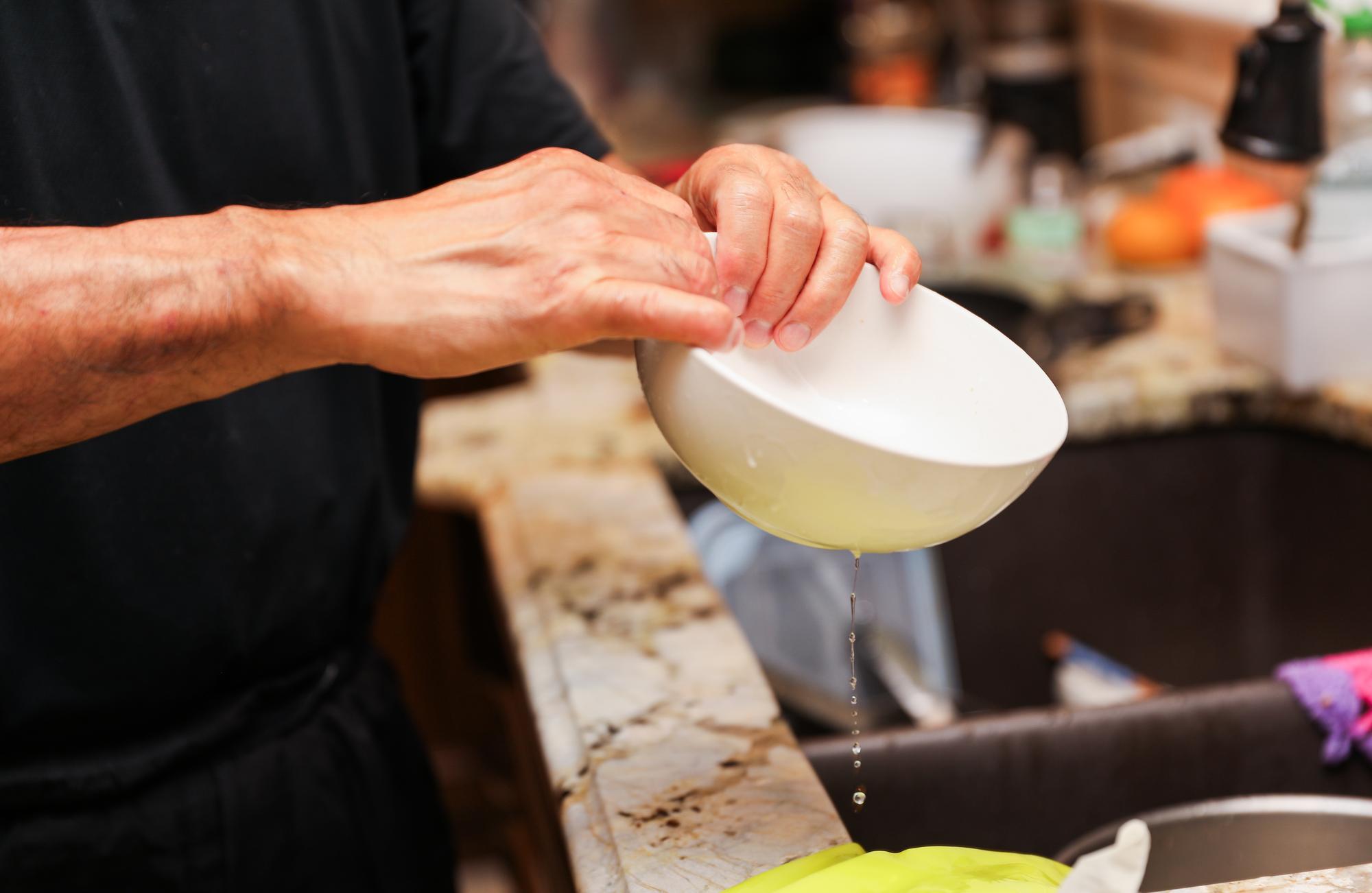 Chef verificând textura unui sos într-un bol ceramic